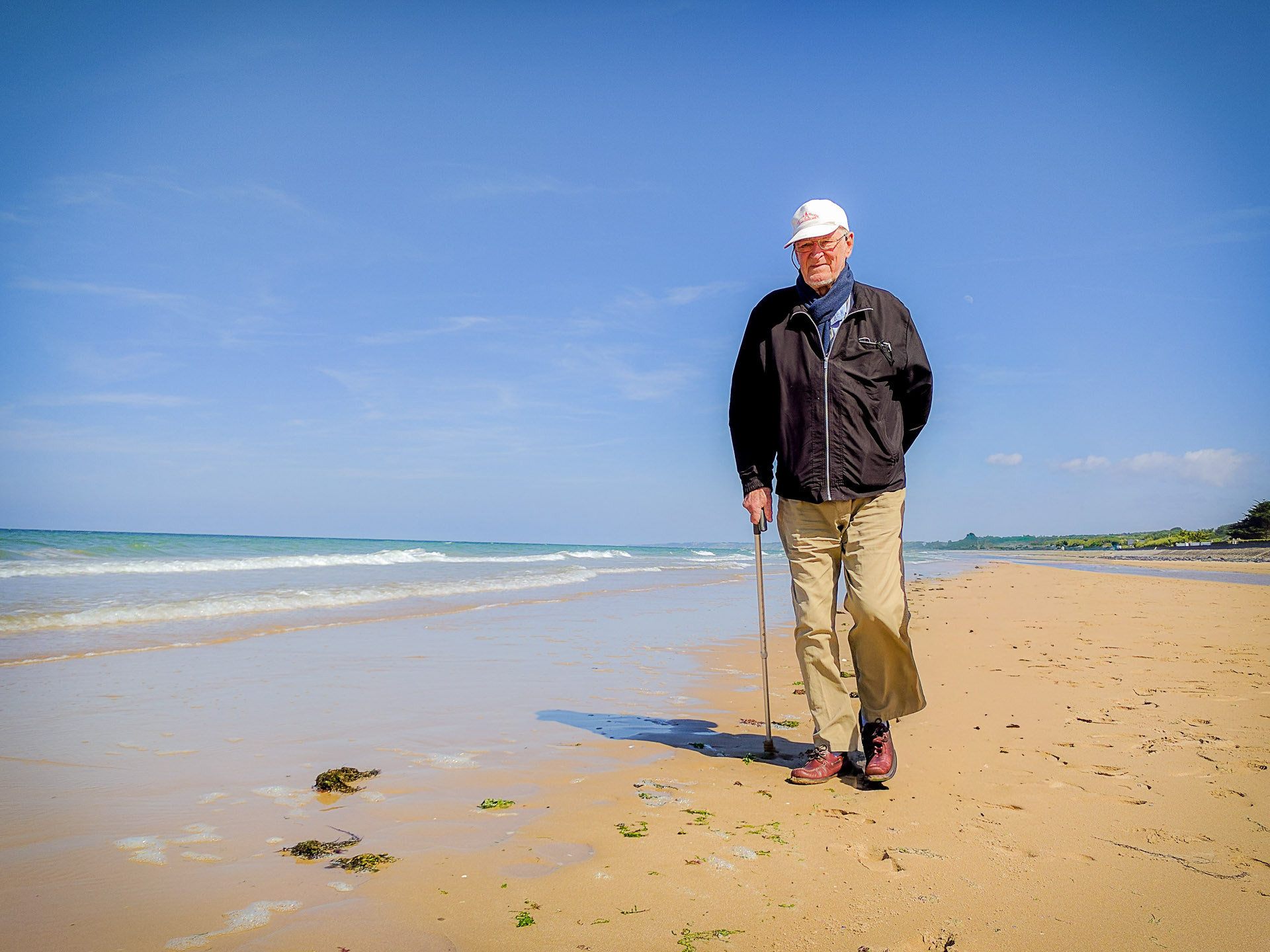 Yves Cordelle, debout sur la plage d’Omaha avec sa canne, face à l’objectif.