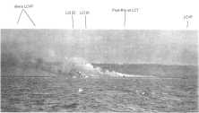 Un LCT sur le point de couler, vu d'un cutter des CG. Il est chargé de Canon de 105 chenillés. A droite un LCML, A gauche, un autre navire, LCT ou LCI. (détails) La plage
