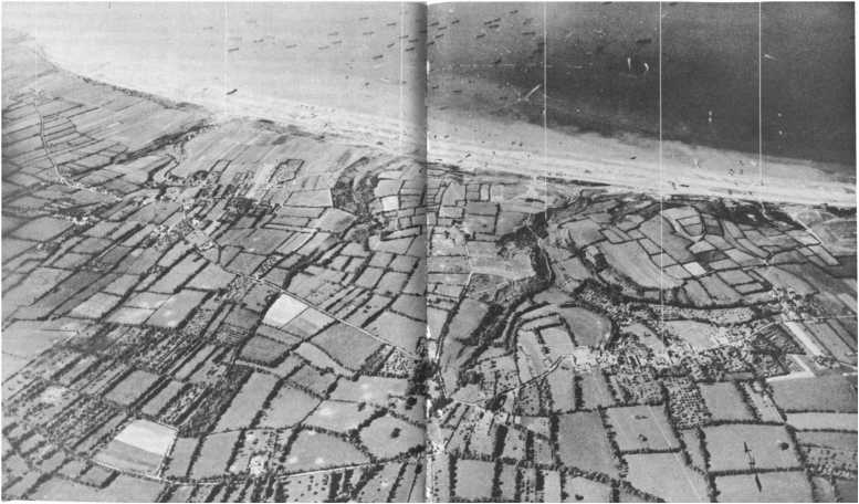 Vue d'ensemble d'Omaha Beach le 7 juin dans l'après midi. Les transports ont quitté leur mouillage au large pour se rapprocher au maximum de la côte. Vierville
