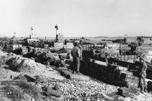 Dépôts sur la plage. Des barges de débarquement échouées et des piles de ravitaillement et munitions. Le LCT-555 est dos à la plage tandis que le LCT(A)(5)-2421 se trouve