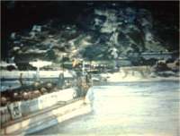 A British LCT is approaching Vierville, in front of the remains of the anti-tank wall on the right. On the left, the beginning of the seafront dam