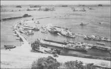 (détails) A gauche le West Pier, devant le Centre Pier, à droite le East Pier et de nombreux LCT appuyés contre les passerelles Les 10 blockships supplémentaires et les 2